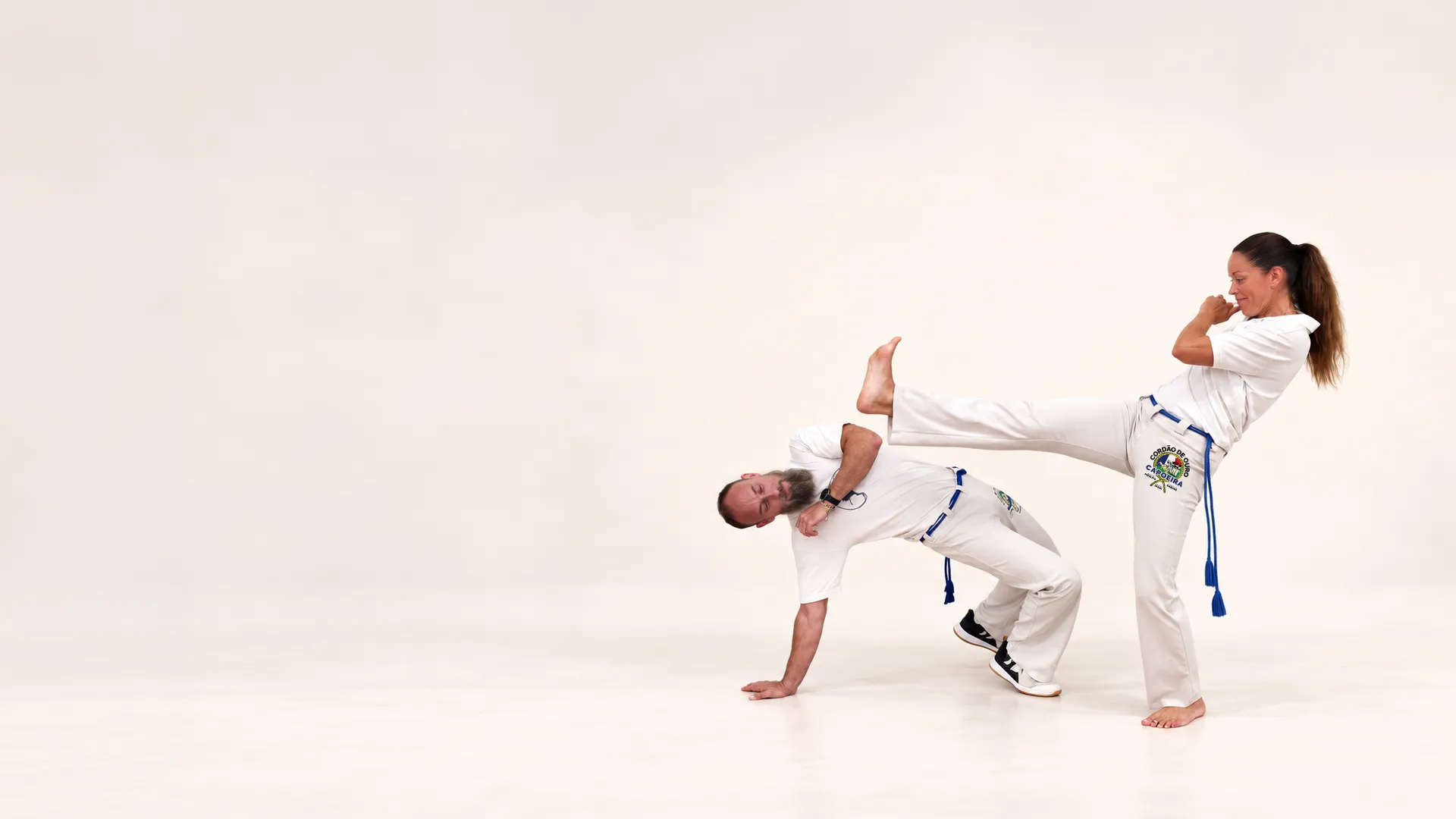 Une capoeiriste lance un coup de pied au-dessus de son partenaire baissé