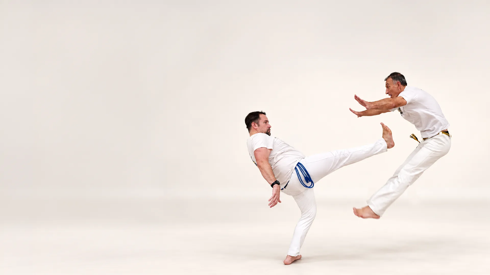 Deux capoeiristes en plein échange, l'un attaque, l'autre esquive en sautant
